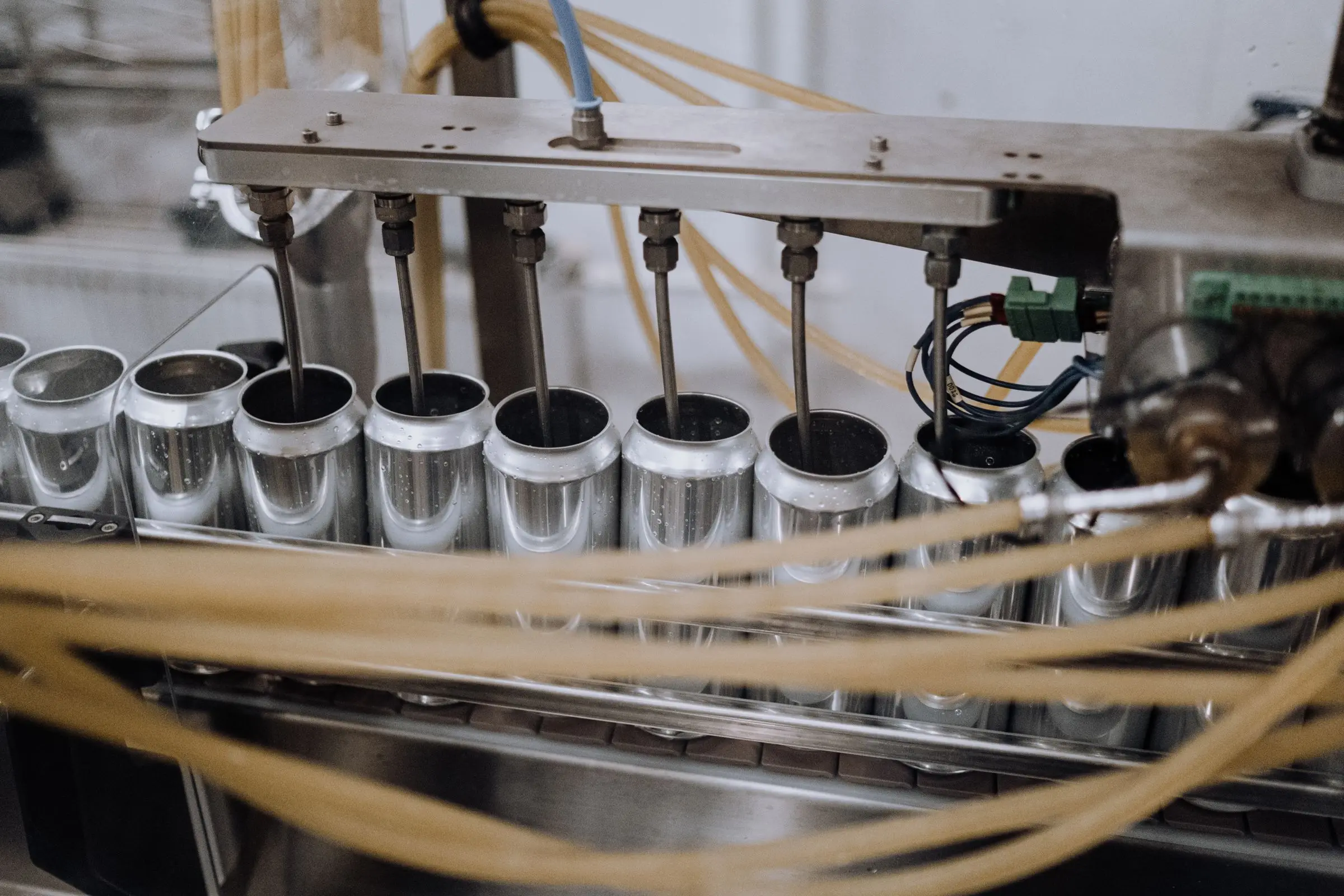 Filling heads lowering into cans on a production line