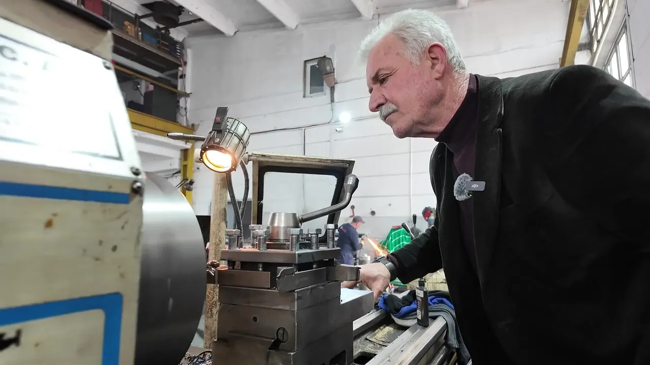 An experienced machinist working at a lathe on a workshop floor