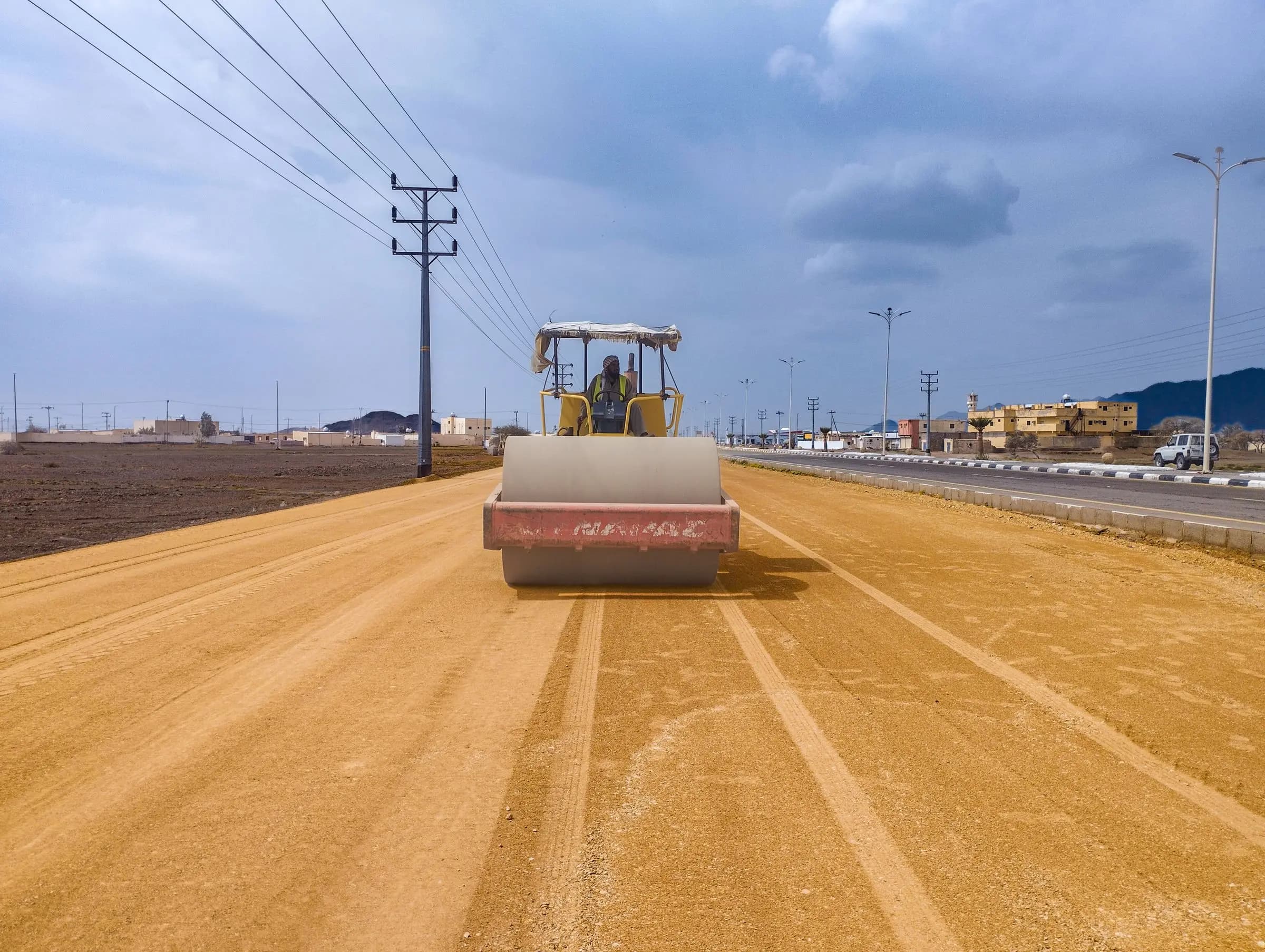 A road roller compacting a new road in the desert