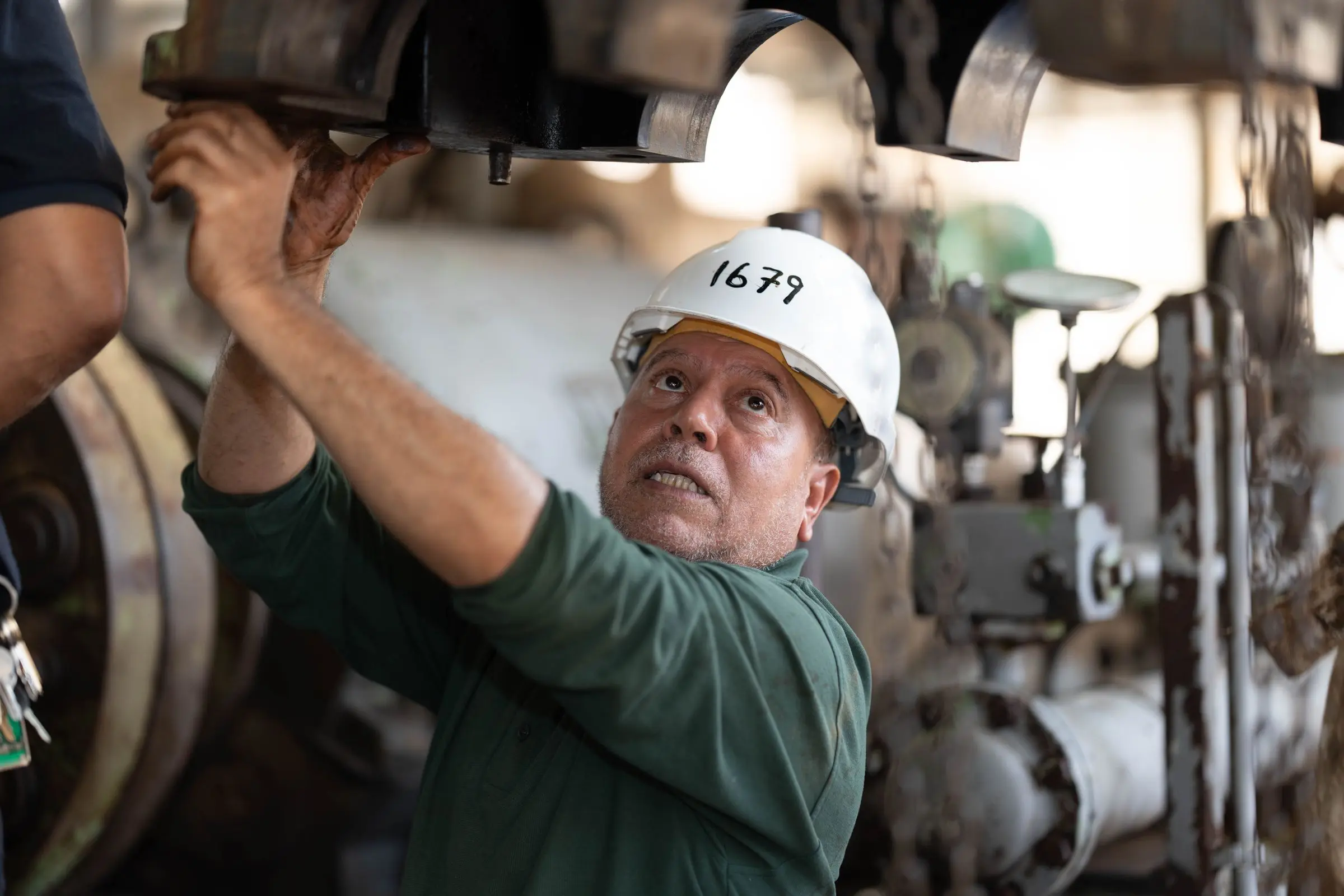 A maintenance technician in a hard hat working on a machine