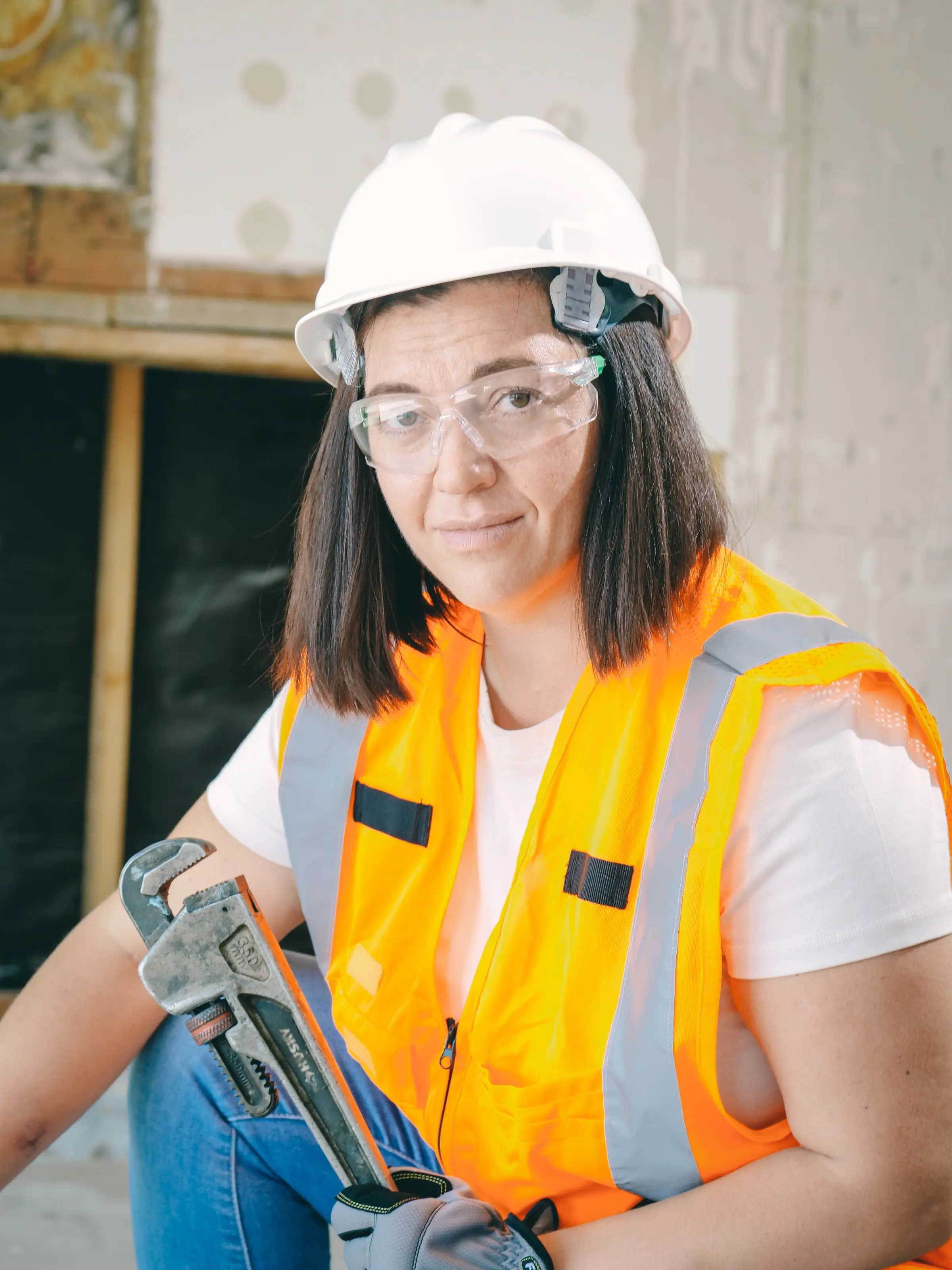 A tradesperson in a safety vest and glasses
